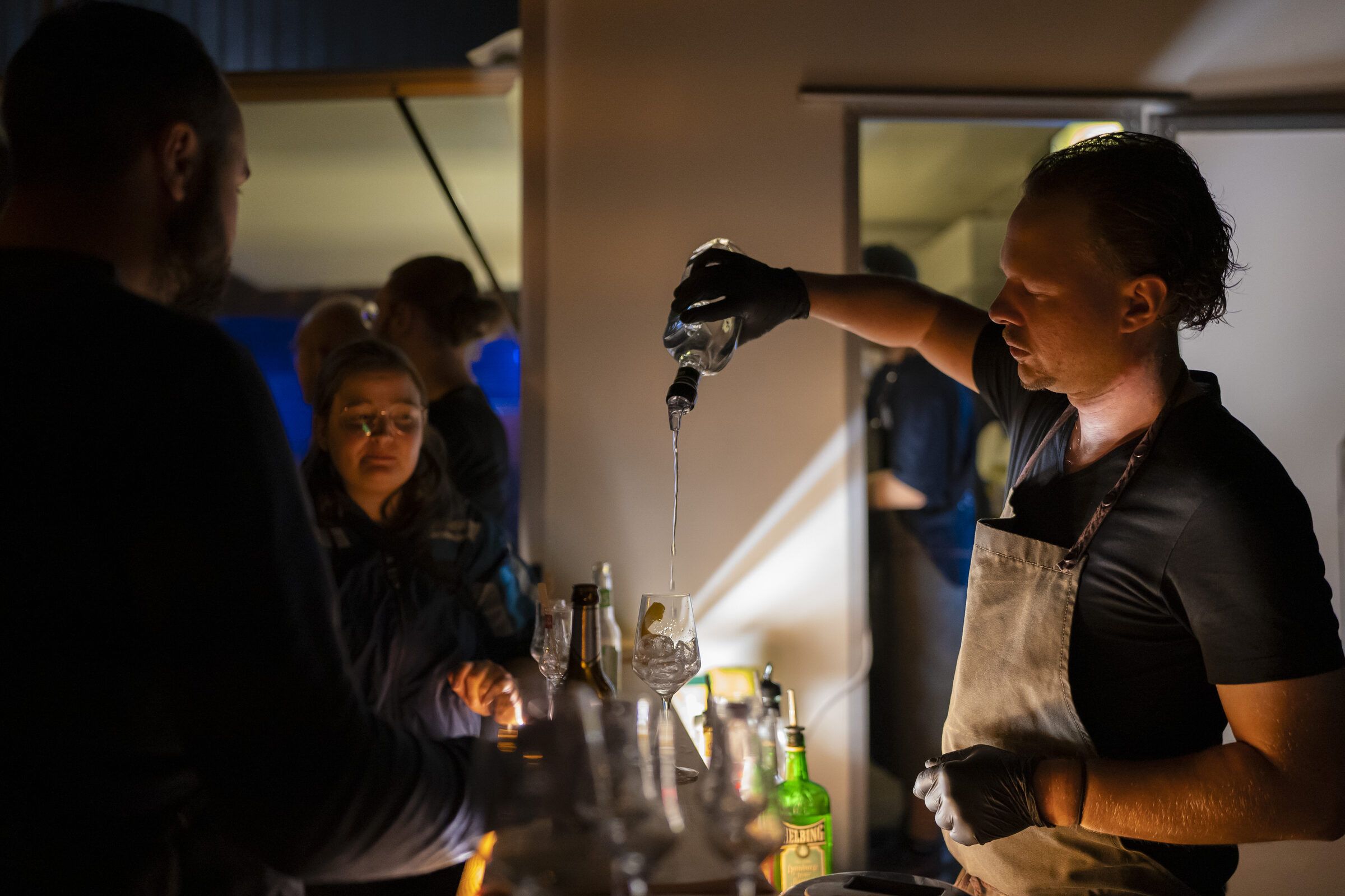 Eine Barkeeperin schenkt an der Bar ein Getränk ein, Gäste warten davor.