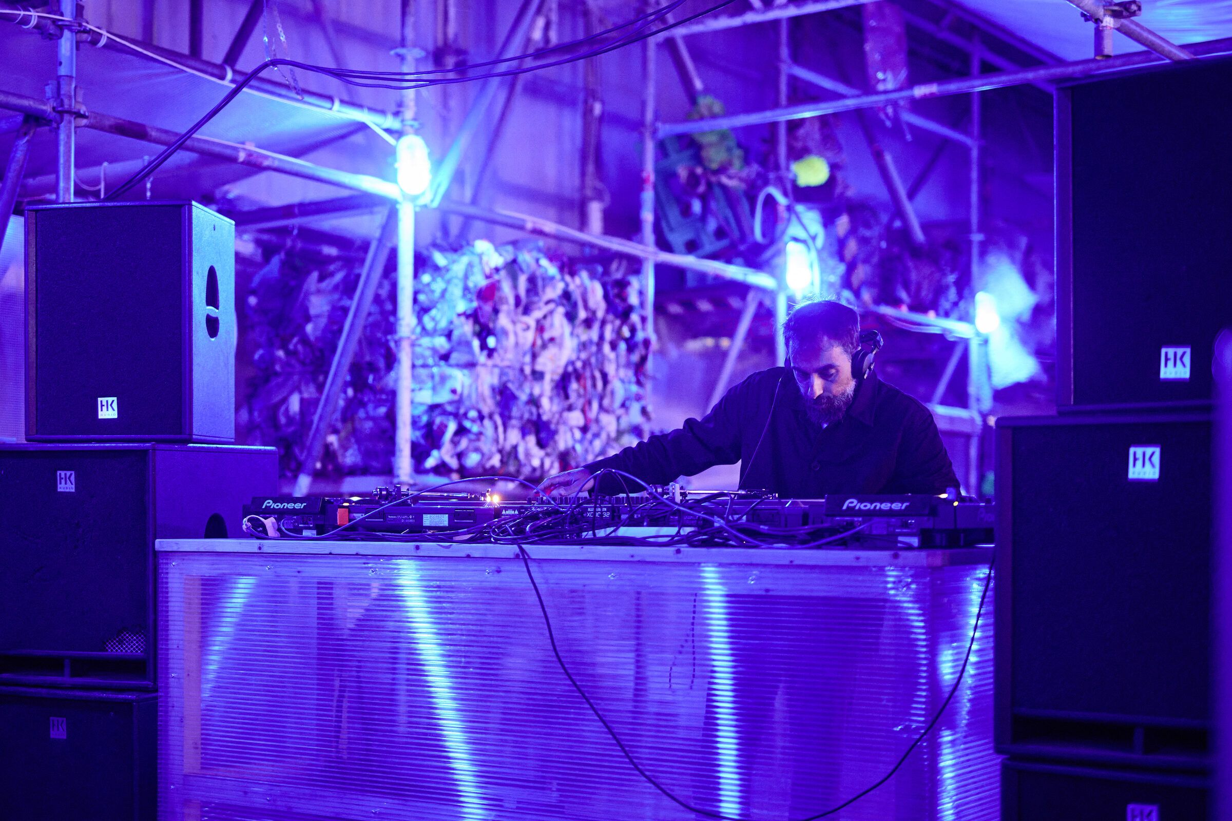 Ein DJ legt am blau beleuchteten Pult zwischen Lautsprechern auf.