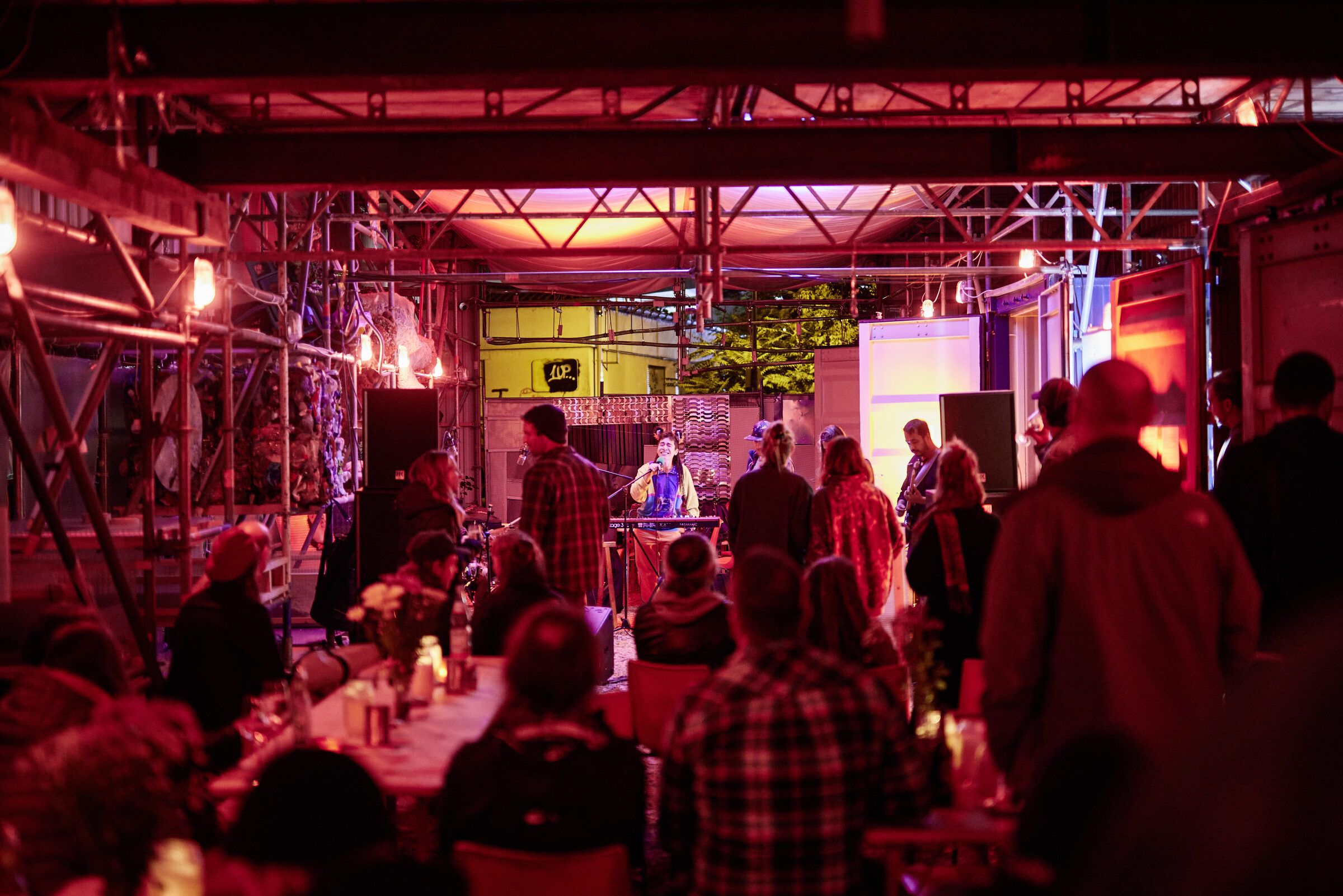 Dicht gedrängtes Publikum in der rot beleuchteten Halle vor dem Konzert.