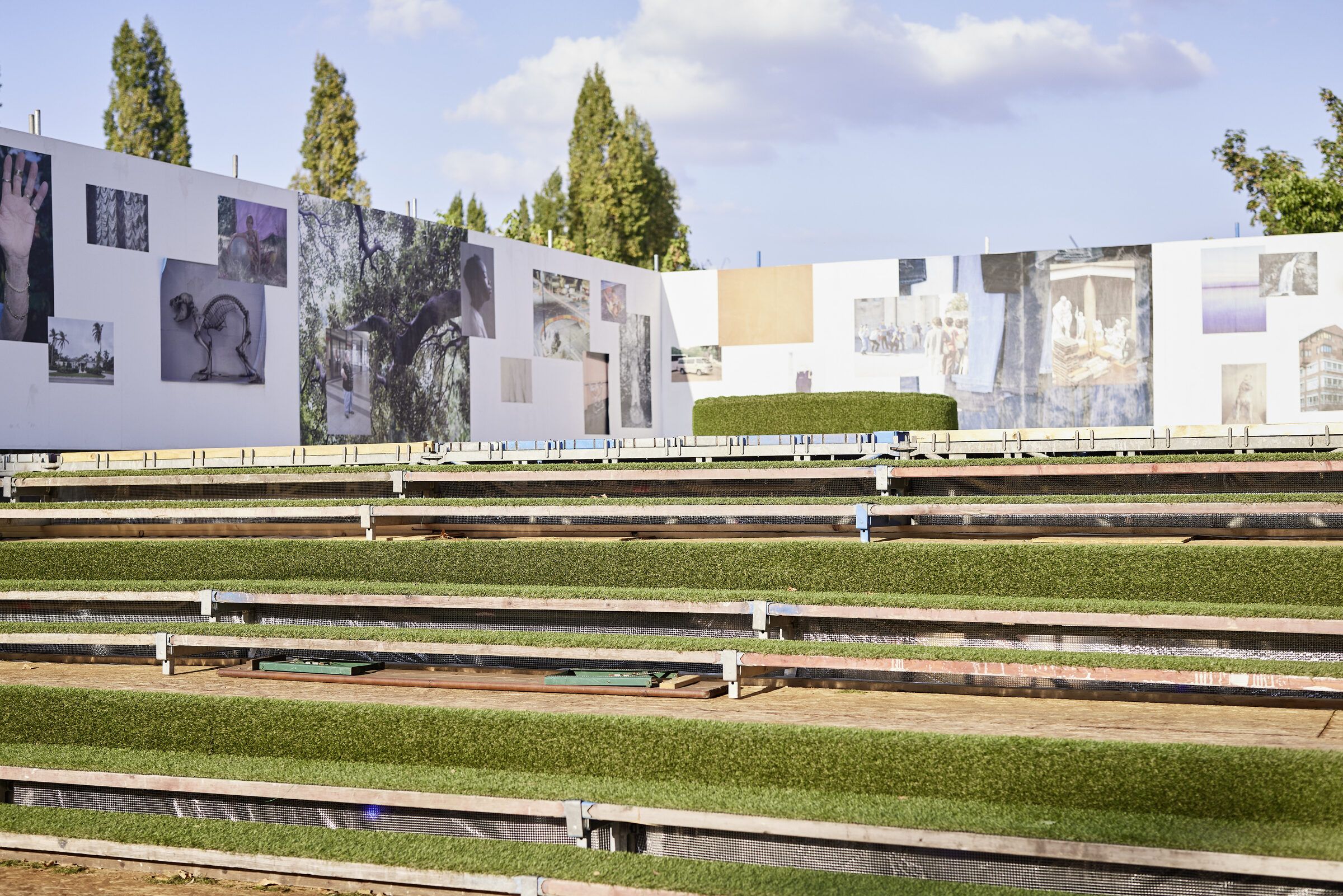 Blick über die begrünten Tribünenstufen auf die Fotowände der oberen Empore.