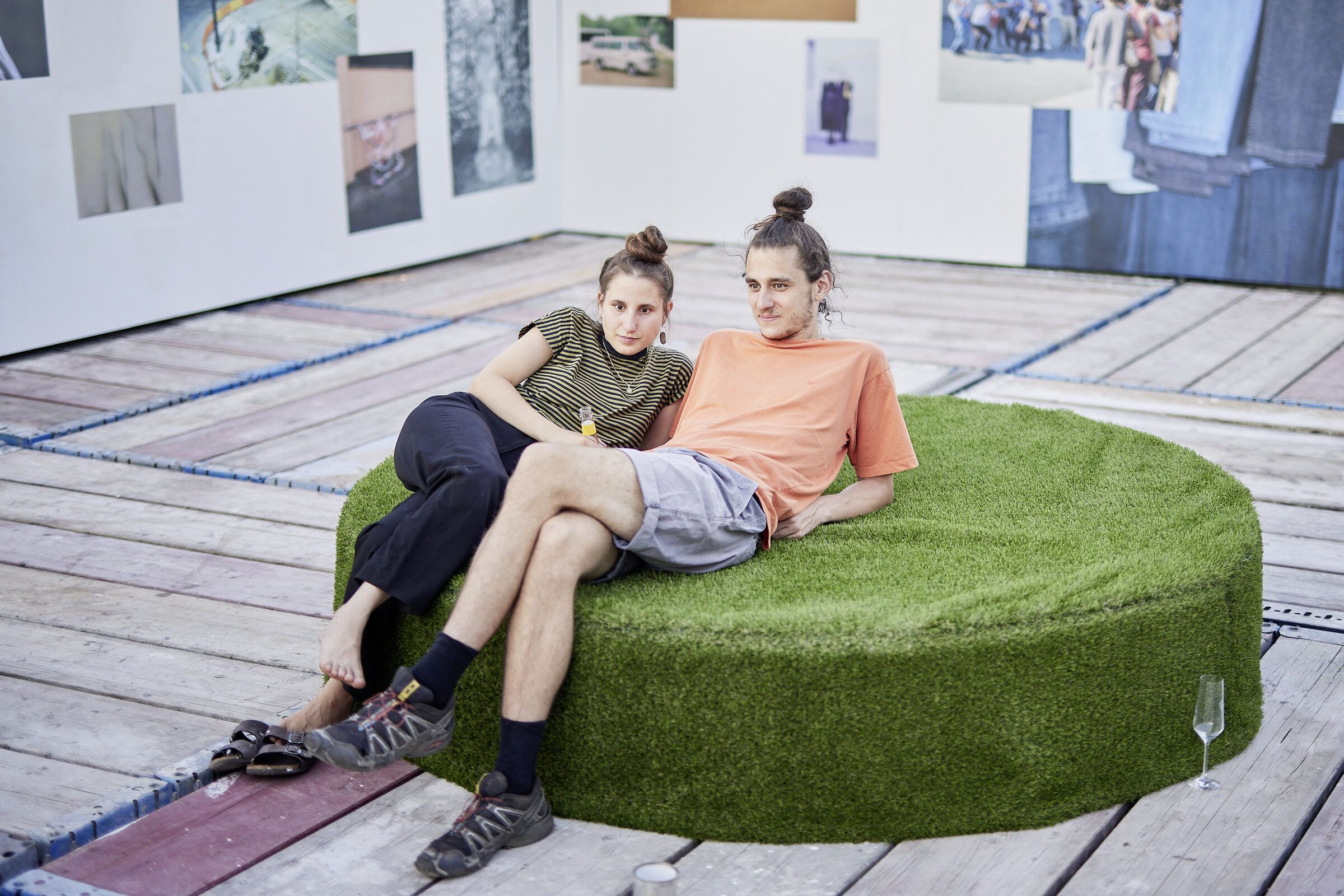 Zwei junge Frauen sitzen entspannt auf einer runden, mit Kunstrasen bezogenen Sitzinsel auf der Dachterrasse.